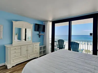 a bedroom with a bed and a mirror and a balcony at Edgewater Windward #304 in Panama City Beach