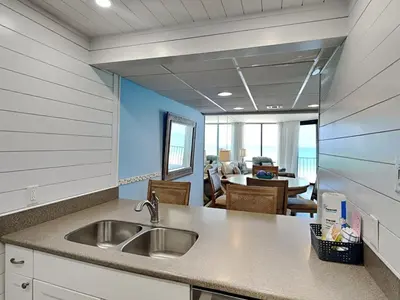 a kitchen with a sink and a dining room at Edgewater Windward #304 in Panama City Beach