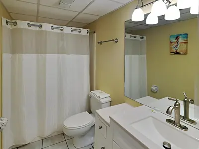 a bathroom with a toilet and a sink and a mirror at Edgewater Windward #305 in Panama City Beach