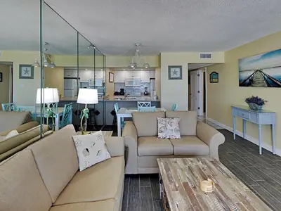 a living room with two couches and a kitchen at Edgewater Windward #305 in Panama City Beach