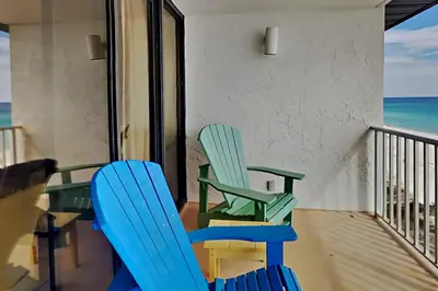 two chairs and a table on a balcony with the ocean at Edgewater Windward #602 in Panama City Beach