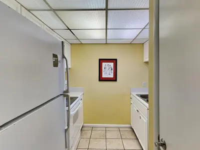 a kitchen with yellow walls and white cabinets at Edgewater Windward #602 in Panama City Beach