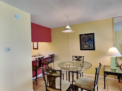 a dining room and kitchen with a glass table and chairs at Edgewater Windward #602 in Panama City Beach