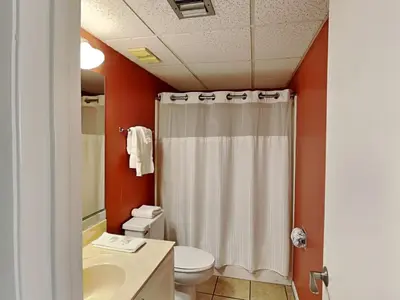 a bathroom with a white shower curtain and a toilet at Edgewater Windward #602 in Panama City Beach