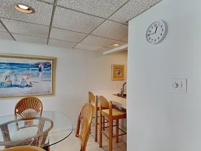 a dining room with a clock on the wall at Edgewater Windward #603 in Panama City Beach
