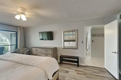 a bedroom with a bed and a television and a bathroom at Edgewater Villa #306 in Panama City Beach