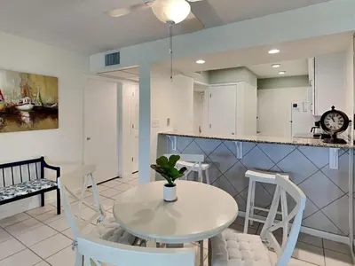 a kitchen and dining room with a white table and chairs at Edgewater Villa #703 in Panama City Beach