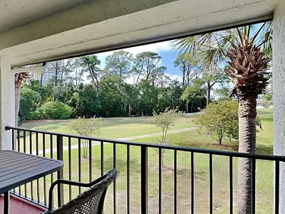 a balcony with a table and a view of a golf course at Edgewater Villa #708 in Panama City Beach