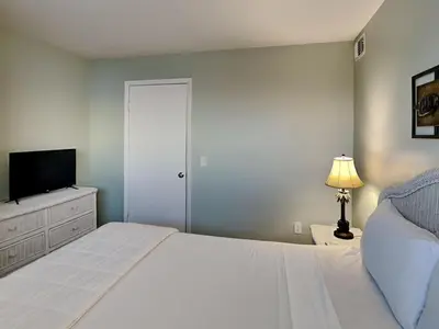 a bedroom with a white bed and a television at Summit Beach Resort #901 in Panama City Beach