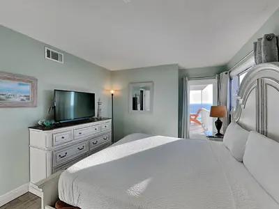 a white bedroom with a bed and a television at Summit Beach Resort #901 in Panama City Beach