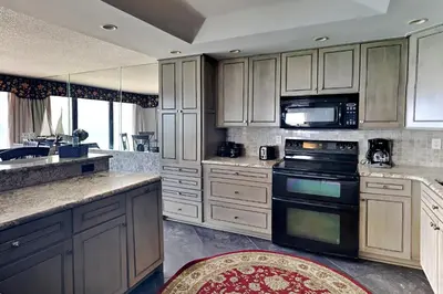 a kitchen with white cabinets and black appliances at Edgewater Tower II 901 in Panama City Beach