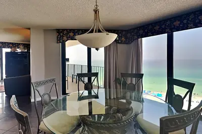 a dining room with a glass table and chairs at Edgewater Tower II 901 in Panama City Beach