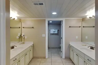 a bathroom with two sinks and two mirrors at Edgewater Tower II 801 in Panama City Beach