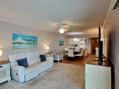 a living room with a white couch and a dining room at Regency Towers 1202 in Panama City Beach