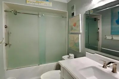 a bathroom with a sink and a toilet and a mirror at Regency Towers 1202 in Panama City Beach