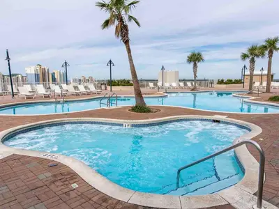 a large swimming pool with a palm tree and chairs at Laketown Wharf 1907 in Panama City Beach