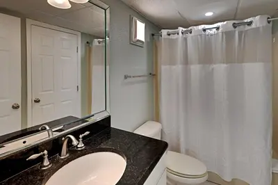 a bathroom with a sink and a toilet and a mirror at Edgewater Tower I 1010 in Panama City Beach