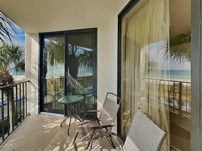 a balcony with chairs and a table and a view of the ocean at Edgewater Tower II 110 in Panama City Beach