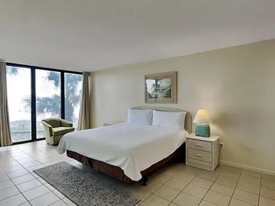 a bedroom with a bed and a chair and a window at Edgewater Tower II 110 in Panama City Beach