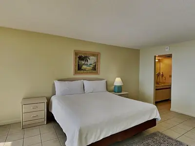 a bedroom with a large white bed and a bathroom at Edgewater Tower II 110 in Panama City Beach