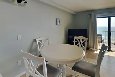 a white dining room with a white table and chairs at Summit Beach Resort #915 in Panama City Beach