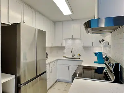 a kitchen with white cabinets and a stainless steel refrigerator at Summit Beach Resort 1230 in Panama City Beach
