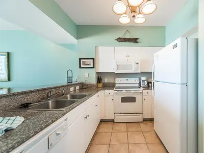 a kitchen with a sink and a refrigerator at Shores of Panama #1111 in Panama City Beach