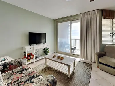 a living room with a couch and a table and a tv at Shores of Panama #1510 in Panama City Beach