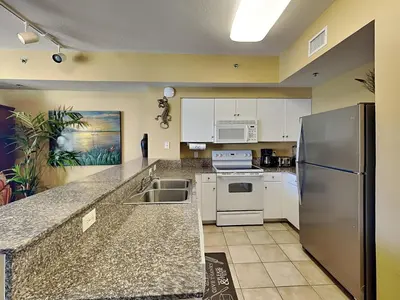 a kitchen with white cabinets and a stainless steel refrigerator at Shores of Panama #1908 in Panama City Beach