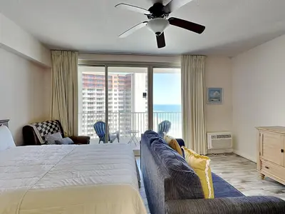 a bedroom with a bed and a couch and a balcony at Shores of Panama #1706 in Panama City Beach