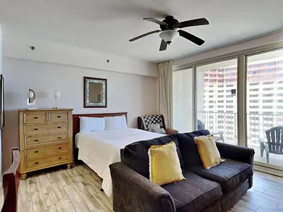 a bedroom with a bed and a couch and a ceiling fan at Shores of Panama #1706 in Panama City Beach