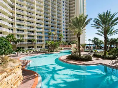 a resort swimming pool with palm trees and a large building at Shores of Panama #1706 in Panama City Beach