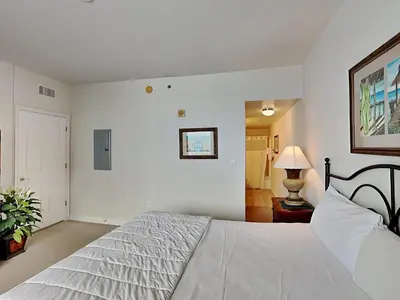 a white bedroom with a bed and a lamp at Shores of Panama #1611 in Panama City Beach