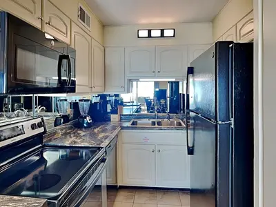 a kitchen with white cabinets and a refrigerator at Summit Beach Resort #429 in Panama City Beach