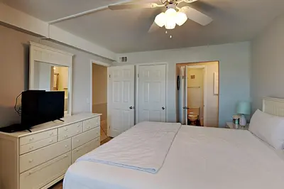 a bedroom with a white bed and a television at Summit Beach Resort 604 in Panama City Beach