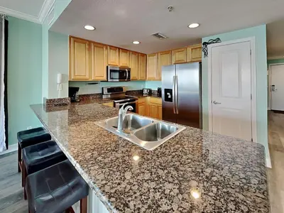 a kitchen with a sink and a stainless steel refrigerator at Grandview East #104 in Panama City Beach