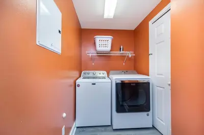 an orange kitchen with a stove and a washer at Grandview East #104 in Panama City Beach