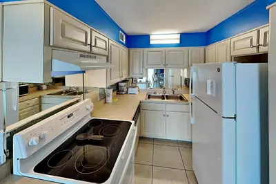 a large kitchen with white appliances and blue walls at Summit Beach Resort in Panama City Beach
