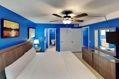 a blue bedroom with a bed and a ceiling fan at Summit Beach Resort in Panama City Beach