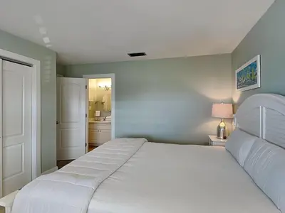 a bedroom with a white bed and a bathroom at Edgewater Villa 1211 in Panama City Beach