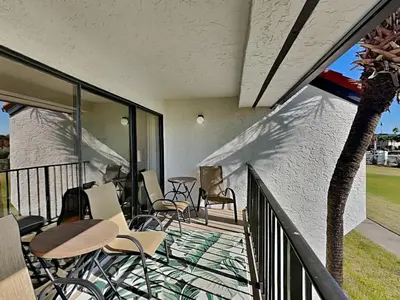 a balcony with chairs and tables and a palm tree at Edgewater Villa 1211 in Panama City Beach