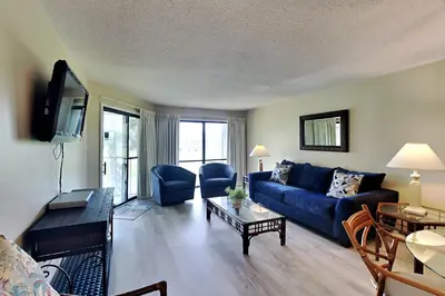 a living room with a blue couch and a table at Edgewater Villa 1410 in Panama City Beach