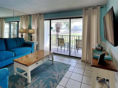 a living room with a blue couch and a table at Edgewater Villa 1509 in Panama City Beach