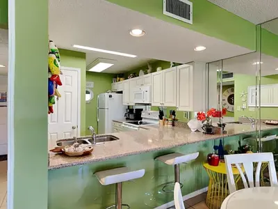 a kitchen with green walls and white cabinets at Edgewater Villa 1702 in Panama City Beach