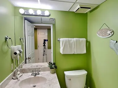 a green bathroom with a toilet and a sink at Edgewater Villa 1702 in Panama City Beach