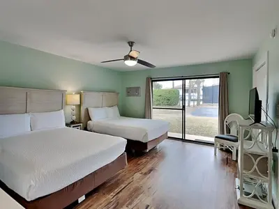 a bedroom with two beds and a tv and a window at Edgewater Villa #2406 in Panama City Beach