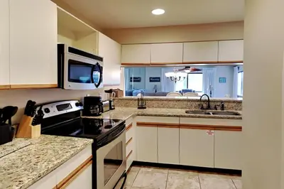 a kitchen with white cabinets and a sink and a microwave at Edgewater Villa #2407 in Panama City Beach