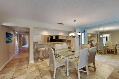 a dining room and living room with a glass table and chairs at Edgewater Villa #2407 in Panama City Beach