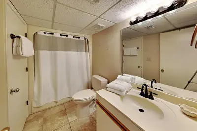 a bathroom with a sink and a toilet and a mirror at Edgewater Villa #2407 in Panama City Beach