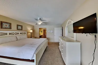 a bedroom with a large bed and a flat screen tv at Edgewater Villa #2407 in Panama City Beach